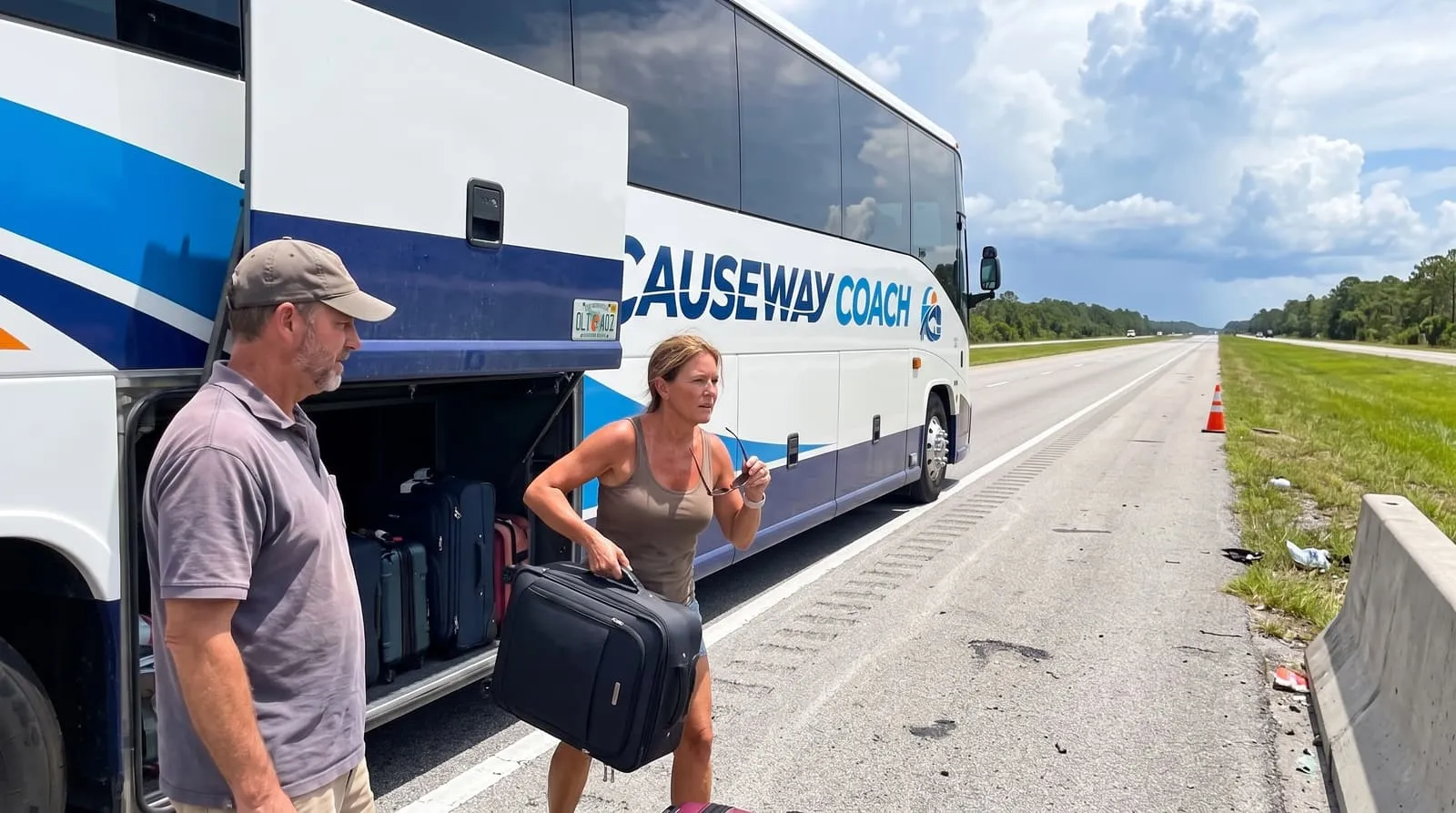 Travellers with suitcases at the open luggage bay of a Causeway Coach motorcoach on a highway approach road in central Florida