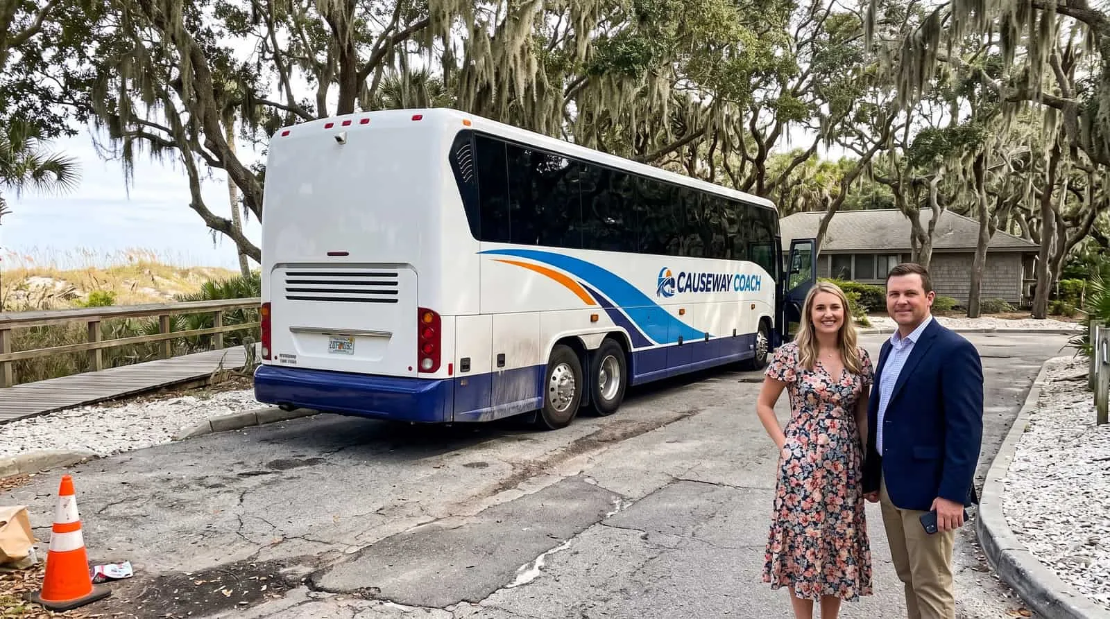 Two wedding guests in smart clothes beside a Causeway Coach motorcoach on a resort access drive on a barrier island near Jacksonville